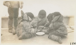 Image of Eskimo [Inuit] children eating on deck of Bowdoin